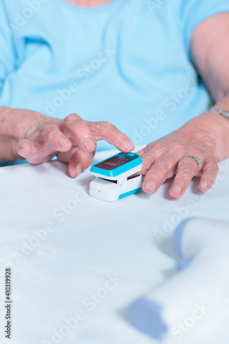 close-up older adult Latina woman doing a test with an oximeter to measure her oxygen levels