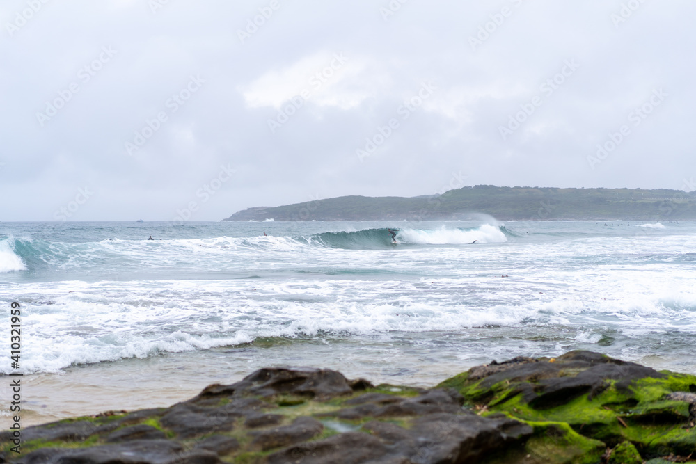 waves at the beach crashing onto the wet green mossy rocks