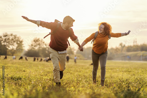 Young happy couple in love holding hands and running in nature. It's a beautiful sunny autumn day. Freedom.