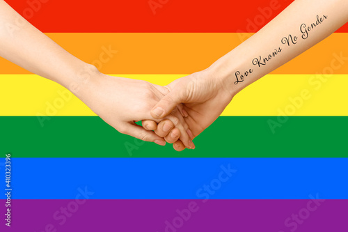 Women holding hands against rainbow flag. LGBT concept