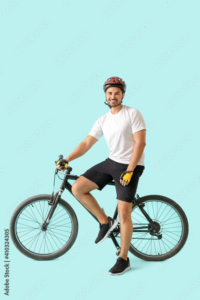 Naklejka premium Male cyclist with bicycle on color background