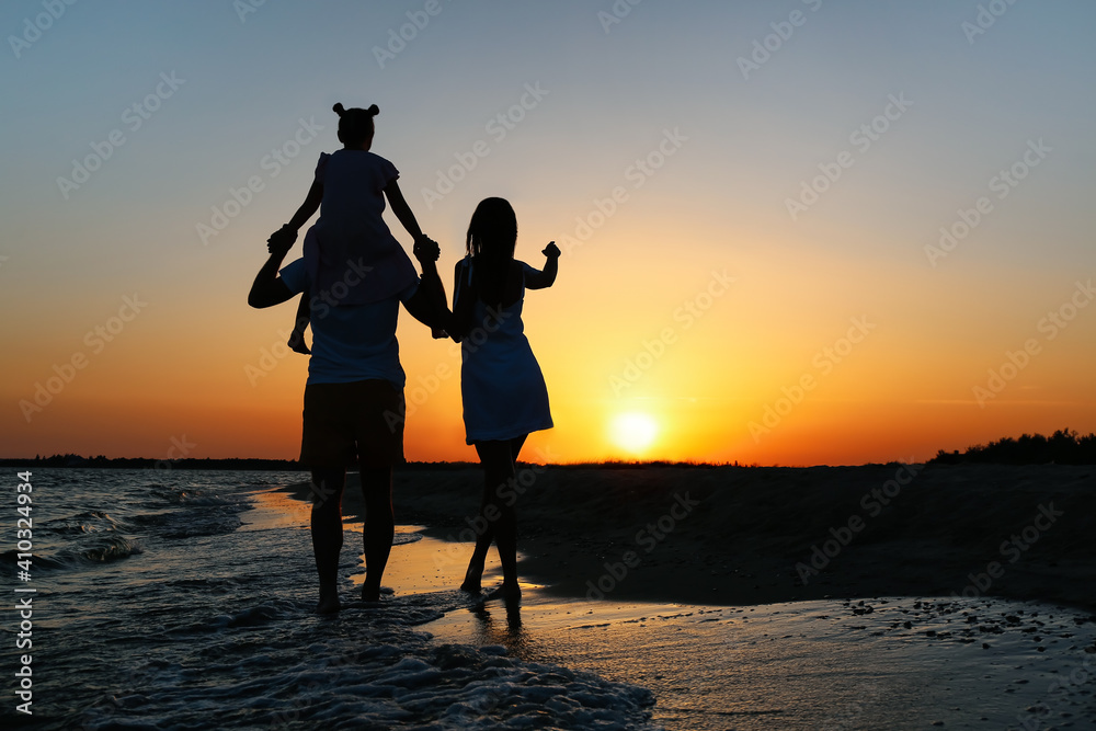 Happy family on sea beach at sunset