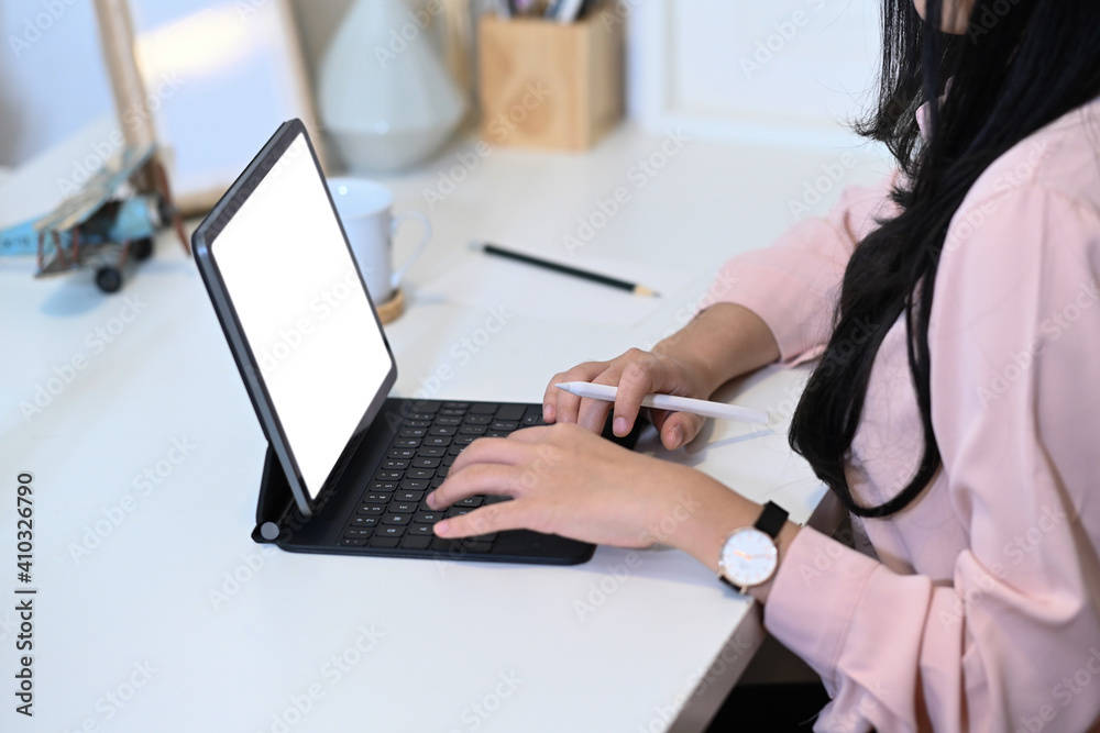 Side view of young woman graphic designer working with tablet computer on office desk. Side view of young woman graphic designer working with tablet computer on office desk.