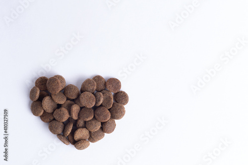 Dry pet food for dogs and cats in the shape of a heart isolated on white background, copy space, top view. The concept of love for pets. Healthy pet food concept