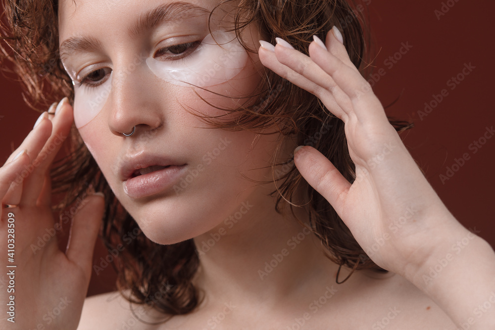Fototapeta premium Eye Skin Beauty. Portrait Of Beautiful Young Female Model With Natural Facial Makeup And Under Eye Care Product On Face On White Background. High Resolution