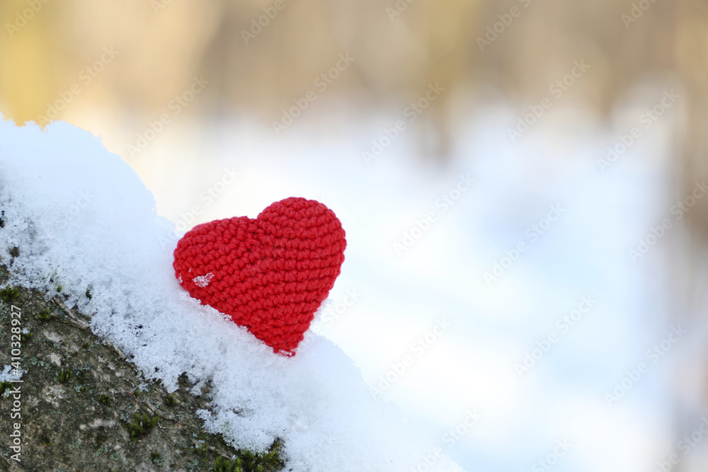 Valentine heart on the snow in sunlight. Red knitted symbol of romantic love on a branch in winter forest, background for holiday Valentine heart on the snow in sunlight. Red knitted symbol of romantic love on a branch in winter forest, background for holiday