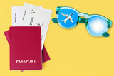 Passport, boarding pass, flight ticket, sunglasses, airplane, shiny sun in blue sky top view close up on yellow background, summer holidays, vacation, travel banner, international tourism, copy space
