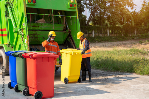 Fotografie Two refuse collection workers loading garbage for trash removal.