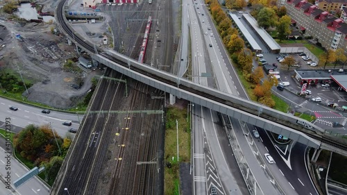 Trains Travelling On Track Going East To Stockholm With Traffic On Road In Gothenburg, Sweden. - aerial photo