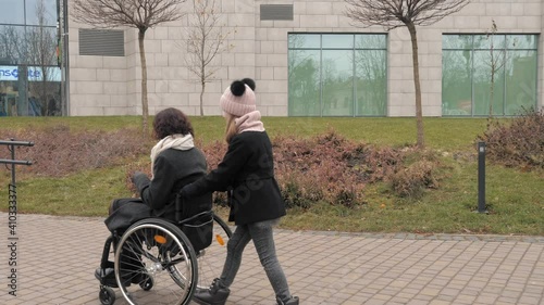 Spending time with relatives. Care and love. Mother in wheelchair with her little daughter spending time together outside.