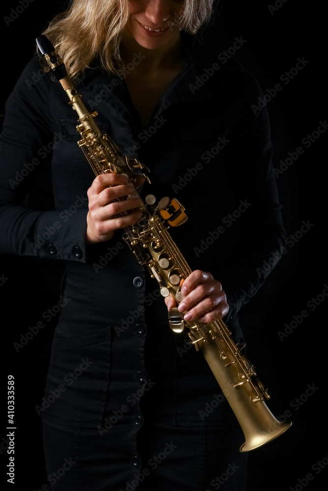 Obraz premium soprano saxophone in the hands of a girl on a black background