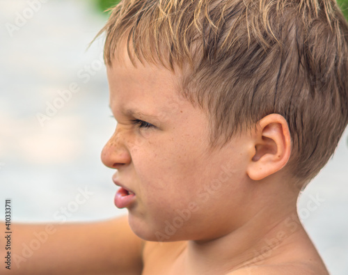 Side portrait mischievous cute blond kid boy, freckled face angry mood disgruntled wrinkled nose facial expression gestures. Childhood relationship behaviour education mental problem parenthood photo