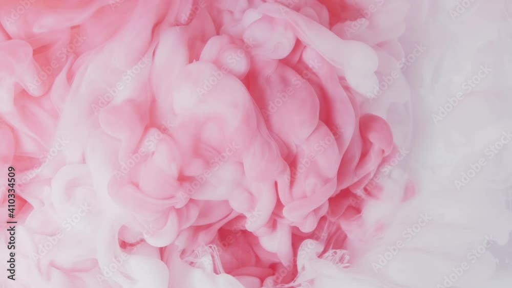 White and pink acrylic paint mixed in water . Slow motion