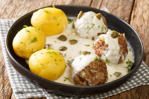 Tasty German Konigsberger Klopse meatballs in caper sauce served with boiled potatoes close-up in a plate on the table. horizontal photo