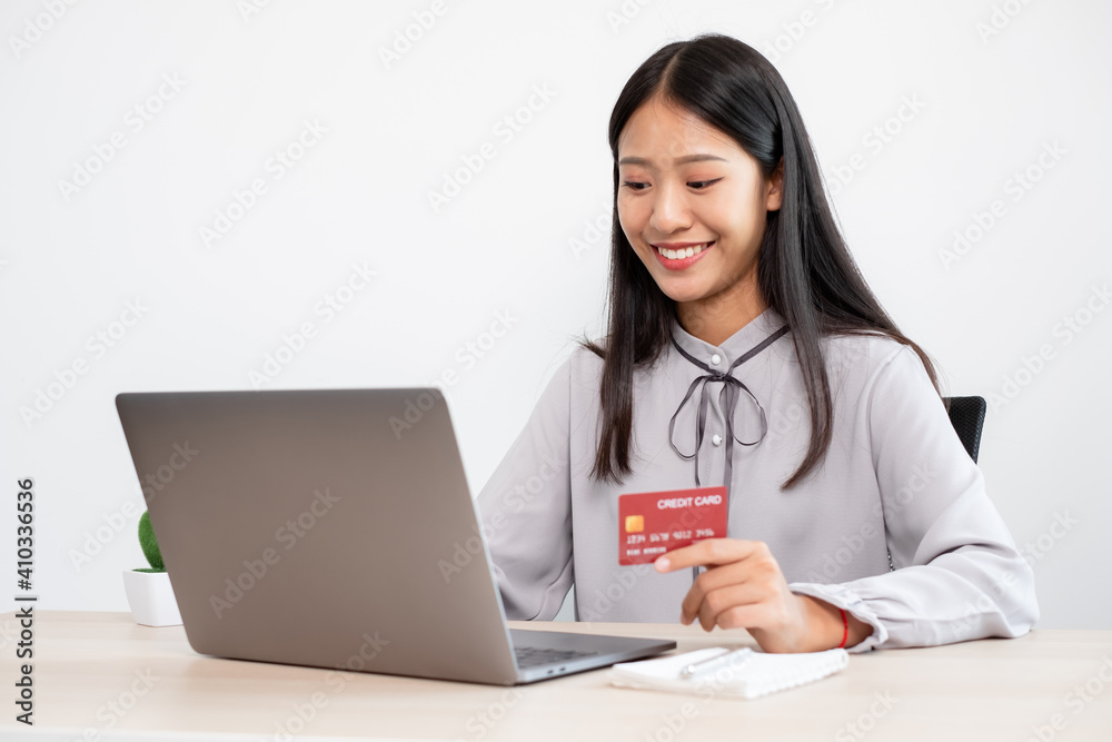 The Asian businesswoman's hand is holding a credit card and using a laptop for online shopping and internet payment in the office The Asian businesswoman's hand is holding a credit card and using a laptop for online shopping and internet payment in the office