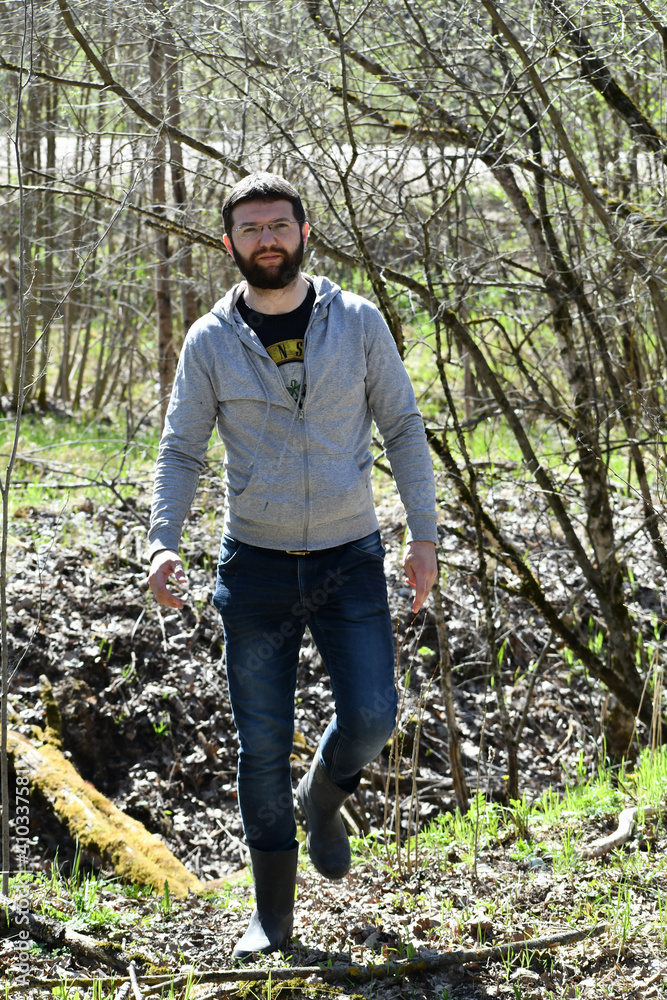 Fototapeta premium A bearded man walks through the spring forest.