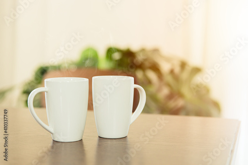 Coffee in the morning, two white tea cup mug placed on wooden table at home.
