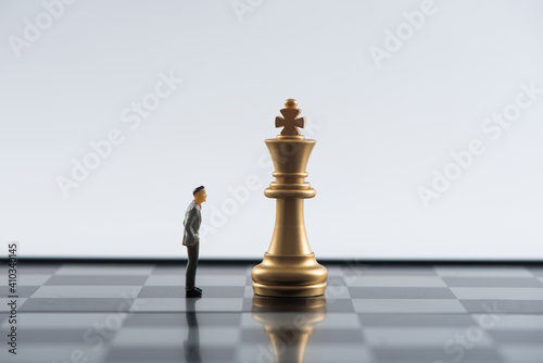 Business and Competition Concept. Businessman miniature figure standing on chessboard with chess pieces