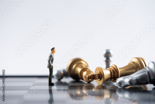 Business and Competition Concept. Businessman miniature figure standing on chessboard with chess pieces photo