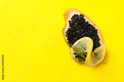 Fototapeta Naklejka Na Ścianę i Meble -  Delicious sandwich with black caviar on yellow background