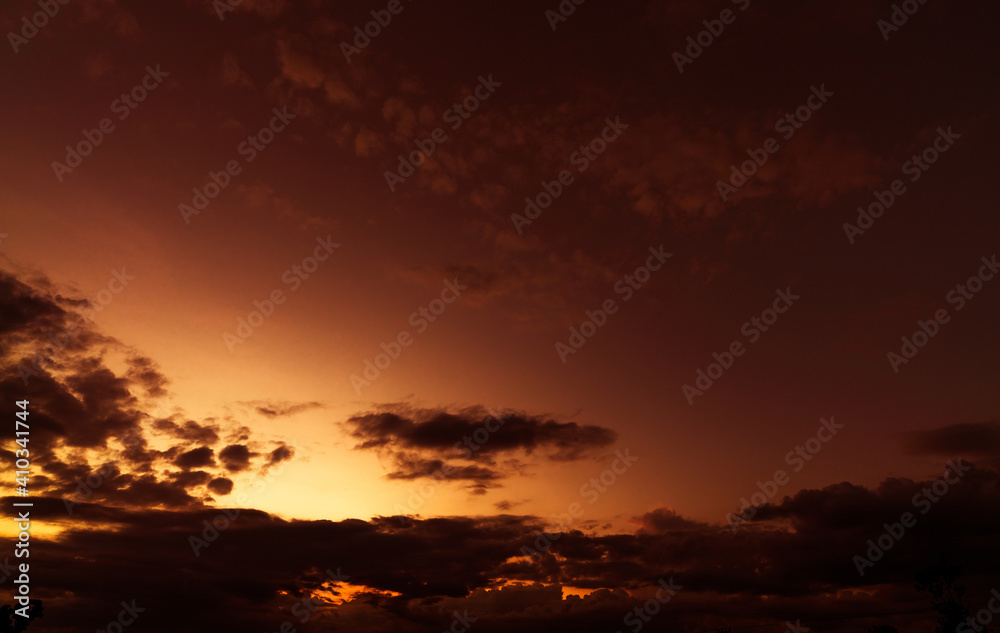 Orange and golden sunset sky with dark clouds. Beauty in nature. Beautiful sunset sky abstract background. Orange and yellow sky with black clouds at dusk. Afterglow. Peaceful and tranquil concept.