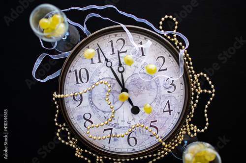 a clock face showing just before midnight on new years eve in Spain with two champagne flutes with twelve grapes