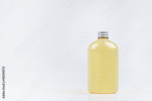 Transparent plastic low thick bottle with orange drink, cooking oil or cosmetic produce with silver cap mockup on white background, template, copy space.