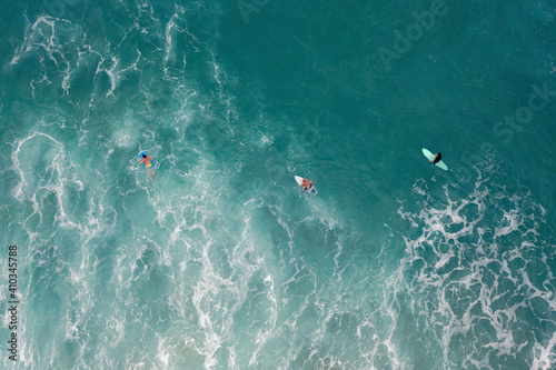Aerial photograph of the ocean with crashed waves and surfers