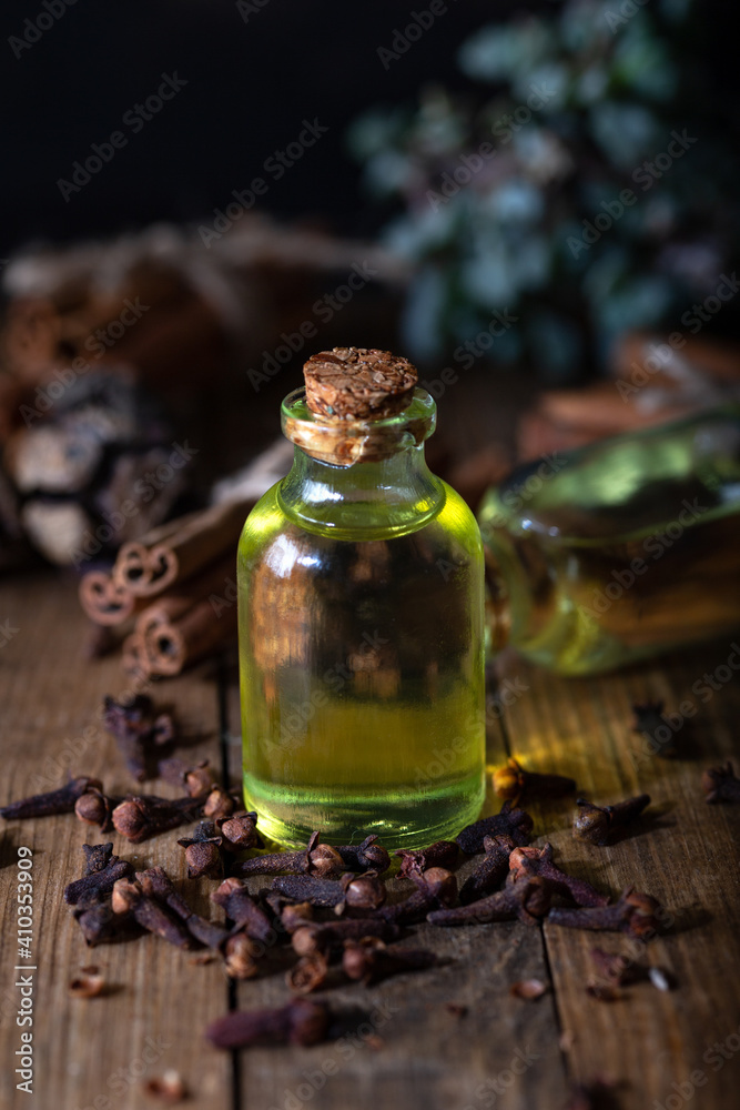Clove oil in a bottle of glass on the table. Bottle of clove essential oil with dried cloves on the wooden background. Clove oil in a bottle of glass on the table. Bottle of clove essential oil with dried cloves on the wooden background.