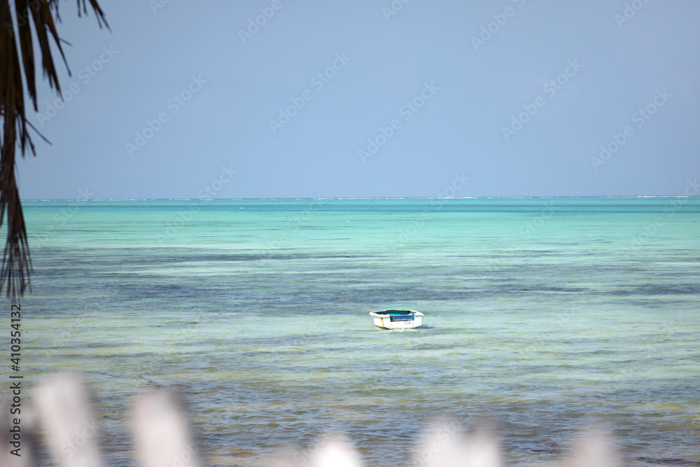 Old wooden boat floating in turquoise water of indian ocean. Tropical climate.