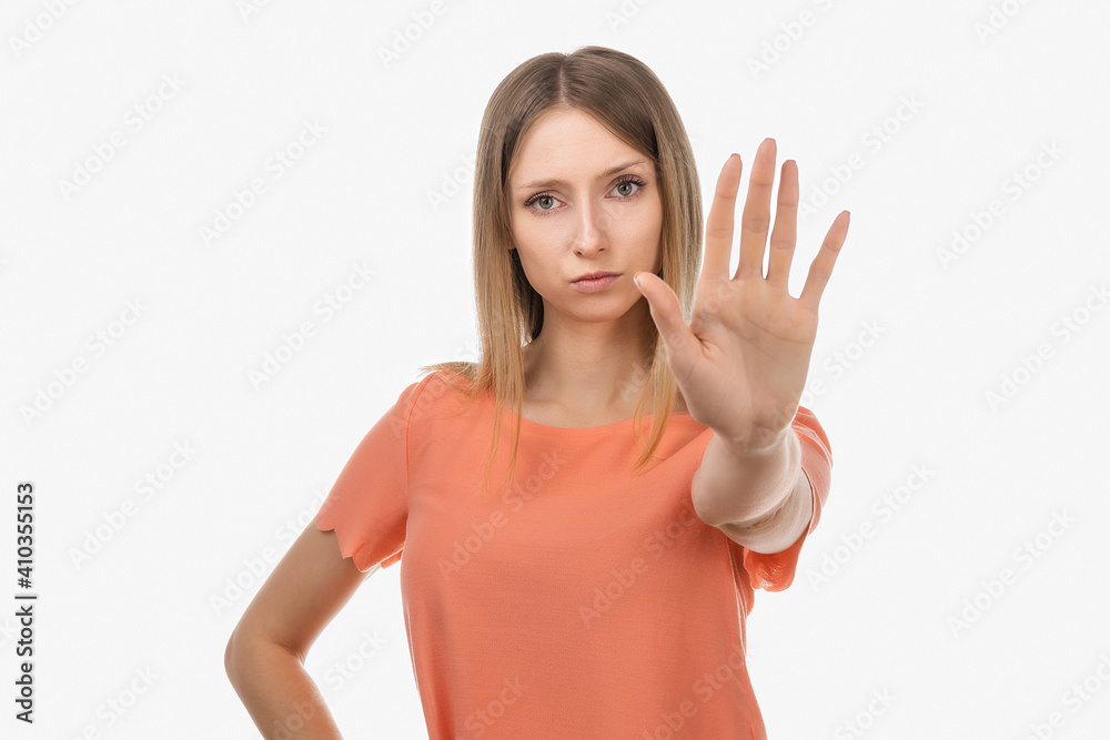 Serious blond girl keeps palm forward at camera, makes forbid sign, restricts or warns, extends arm in stop sign Serious blond girl keeps palm forward at camera, makes forbid sign, restricts or warns, extends arm in stop sign
