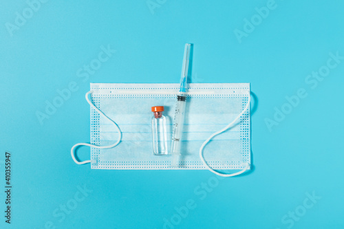 Medical Mask, Plastic Syringe And Bottle On Blue Background Top View.