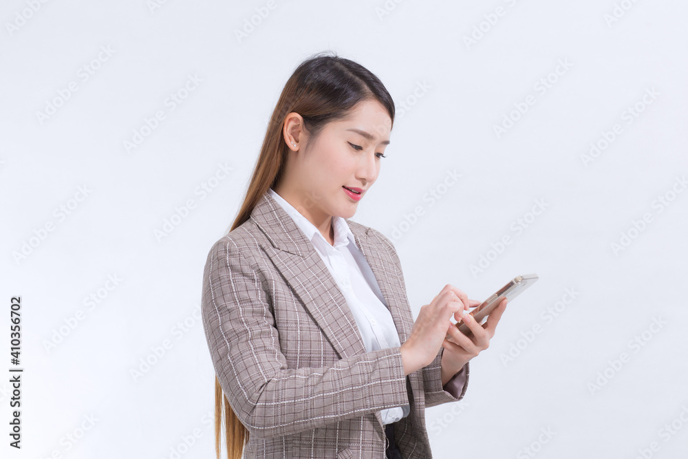 An Asian working woman in a formal suit in a white shirt is making a phone call to check information. An Asian working woman in a formal suit in a white shirt is making a phone call to check information.