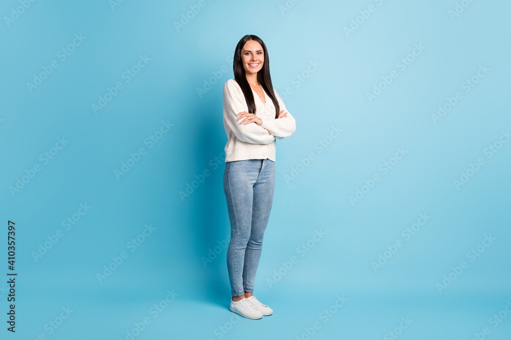 Full length profile portrait of half turned nice girl crossed arms smile look camera isolated on blue color background Full length profile portrait of half turned nice girl crossed arms smile look camera isolated on blue color background