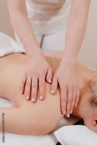 Back massage. The masseuse massages the woman's back. Hand movements of the masseur.