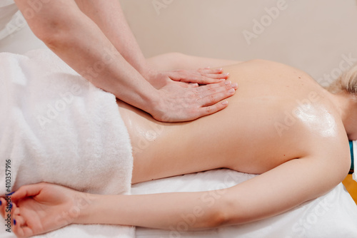 Back massage. The masseuse massages the woman's back. Hand movements of the masseur.
