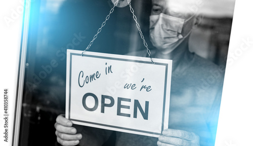 Store owner hanging open sign on window; light effect