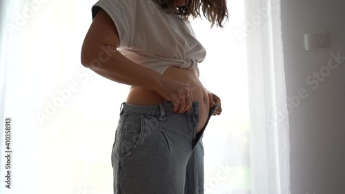 Womanl tries to button up jeans. Overweight, full tummy, postpartum recovery psychological problems, weight loss diet concept
