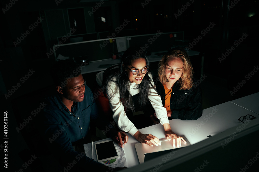 Obraz premium Successful multiethnic business team working on laptop over office desk at night