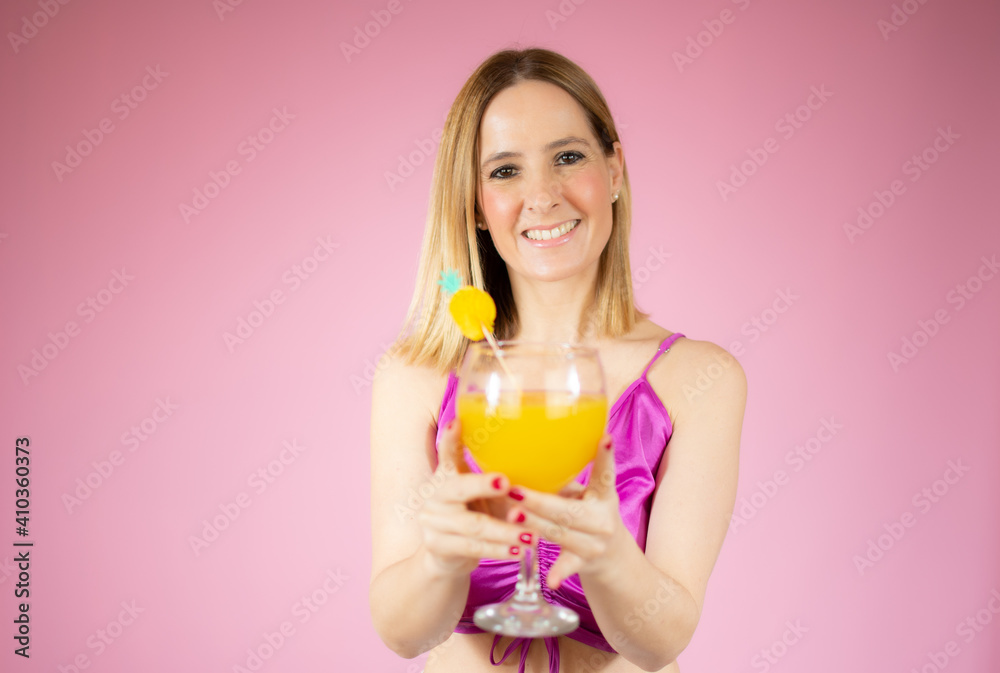 Young beautiful blonde woman drinking glass of healthy orange juice over pink background Young beautiful blonde woman drinking glass of healthy orange juice over pink background
