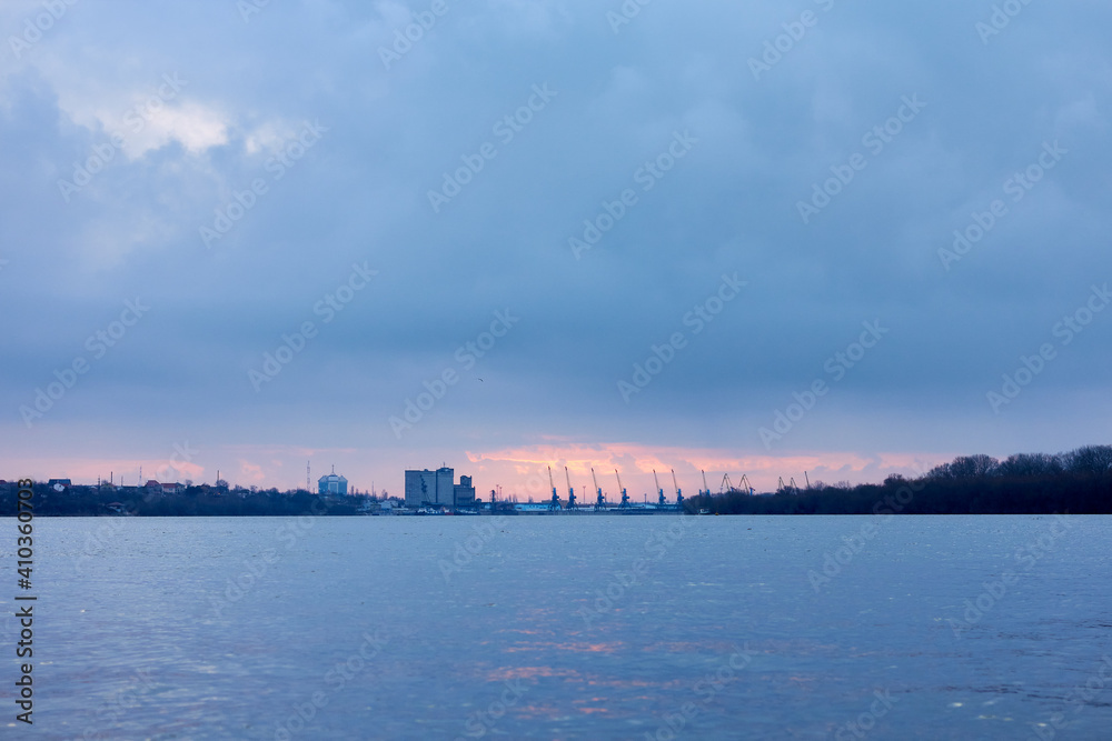 winter landscape - a river, a cargo port and cloudy sky