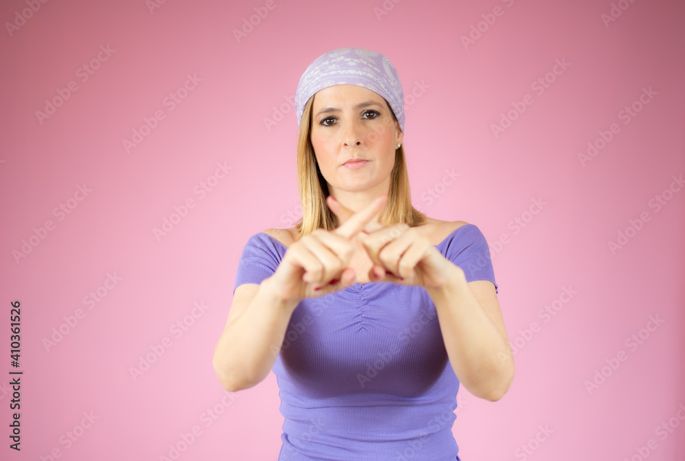 Young woman wearing casual t-shirt standing over pink isolated background rejection expression crossing fingers doing negative sign Young woman wearing casual t-shirt standing over pink isolated background rejection expression crossing fingers doing negative sign