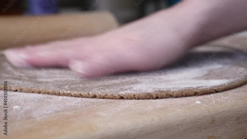 Female hands cutting out gingerbread houses.