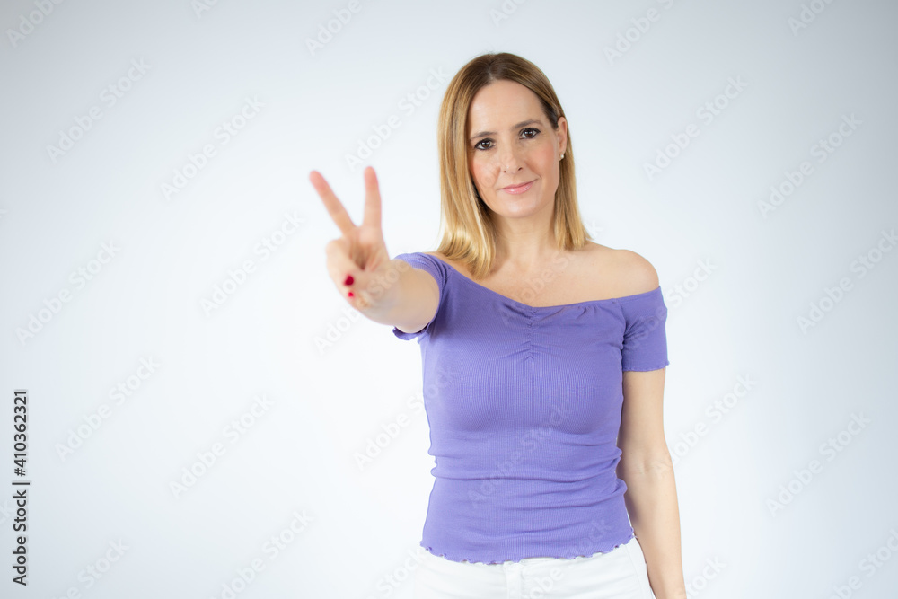 Young beautiful woman wearing casual t-shirt smiling looking to the camera showing fingers doing victory sign. Number two. Young beautiful woman wearing casual t-shirt smiling looking to the camera showing fingers doing victory sign. Number two.