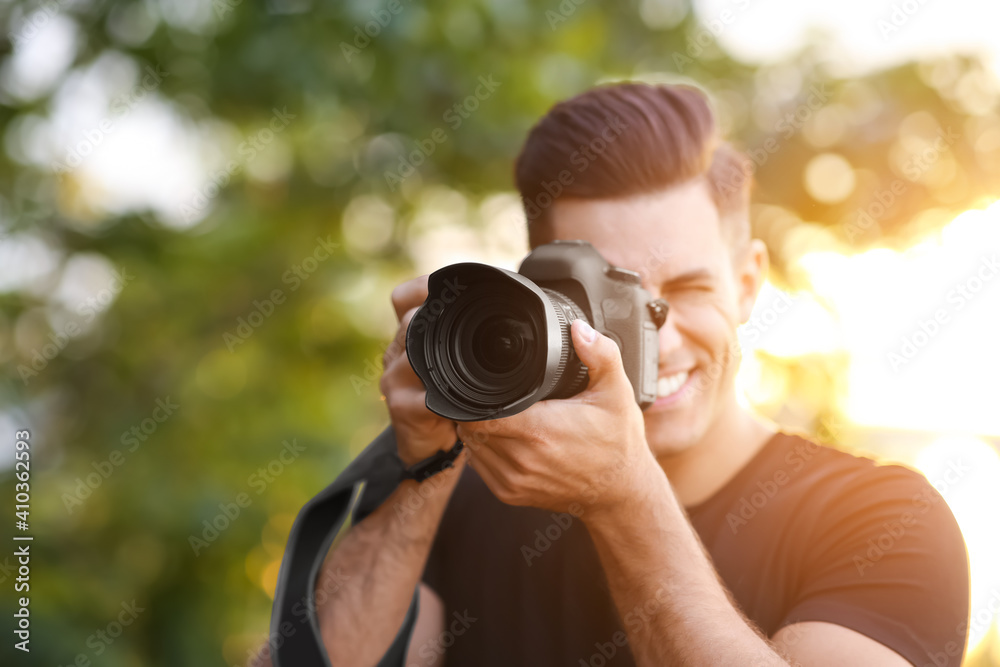 Photographer taking picture with professional camera in countryside, focus on lens Photographer taking picture with professional camera in countryside, focus on lens
