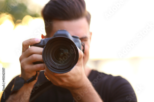 Photographer taking picture with professional camera in countryside, focus on lens