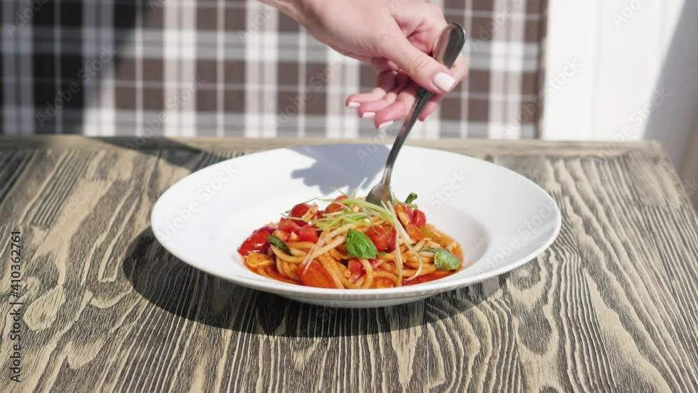 Italian cuisine in restaurant eating spaghetti pasta with vegetables with a fork closeup Italian cuisine in restaurant eating spaghetti pasta with vegetables with a fork closeup