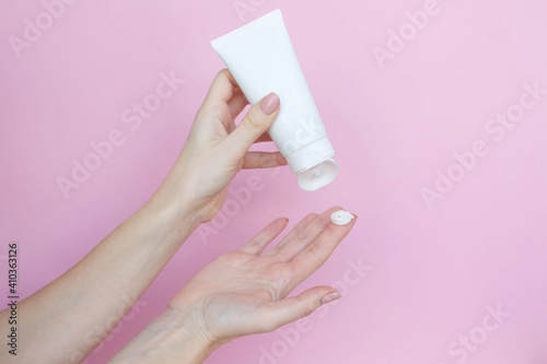 Woman's hands with a tube and a swatch of cream on a pink background. Cosmetic products concept. Copy space © Kate