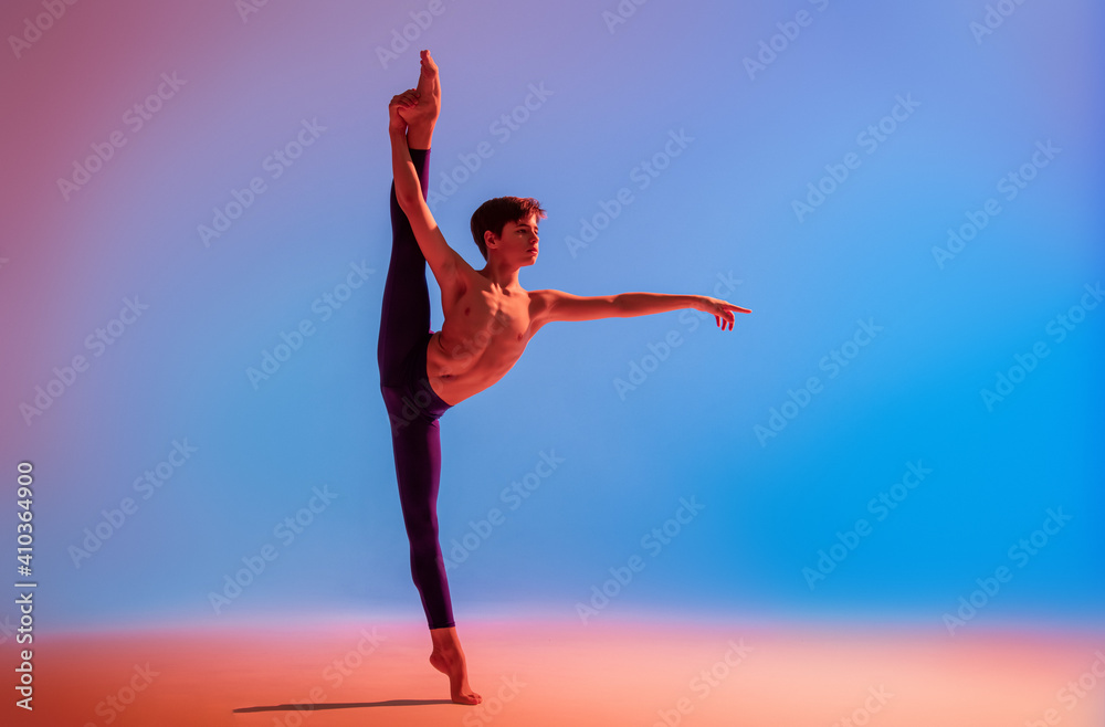 Fototapeta premium teenage ballet dancer dances barefoot under colored light.