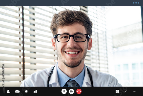 Young doctor smiling to the camera while making video call with patient online, home medical consulation service concepts photo